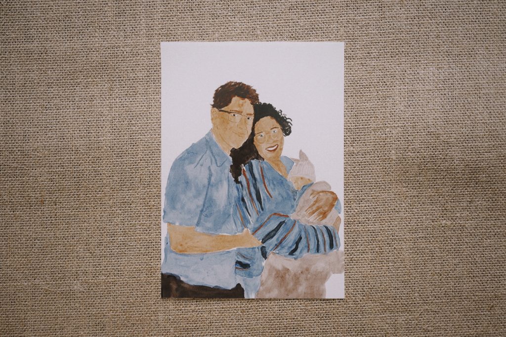Custom watercolor portrait of a couple with a baby, created by Warm Regards Studio.