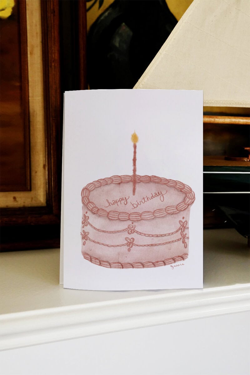 Greeting card featuring a birthday cake with a lit candle and "happy birthday" message.